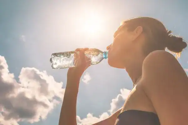 Hydration: The Secret Ingredient for a Toned Stomach and Enhanced Fitness 3 Image of woman drinking water to hydrate Amersham after run.